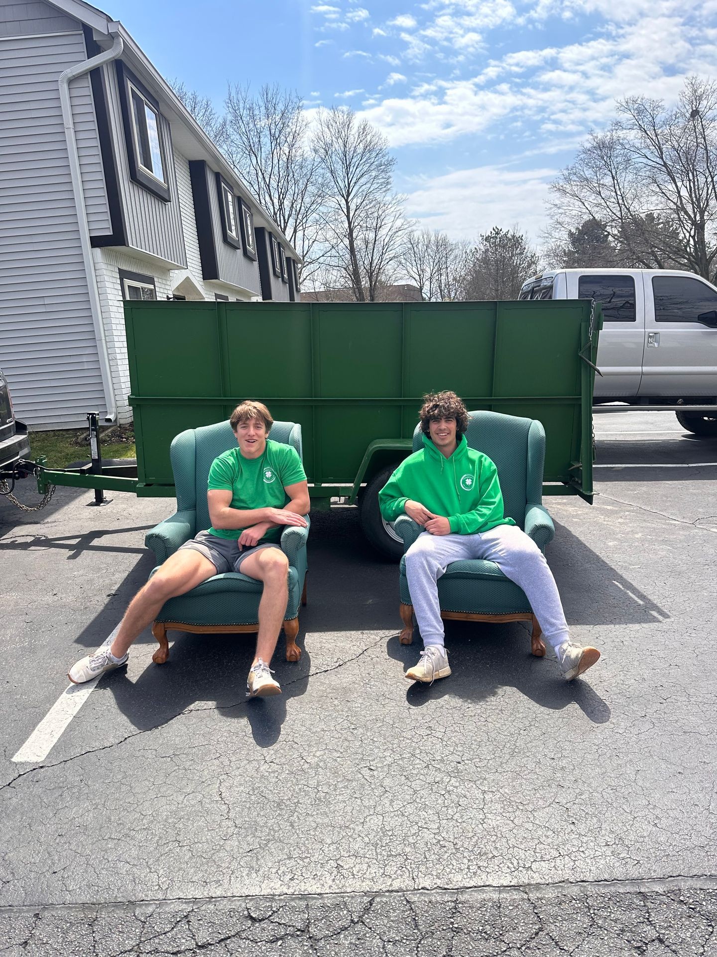 Two Shamrock Junk Removal Employees sitting in front of our 7 yard trailer